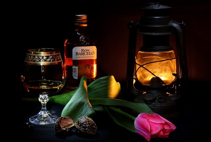 Ron Barcelo rum bottle, glass, chocolates, tulip, and lantern