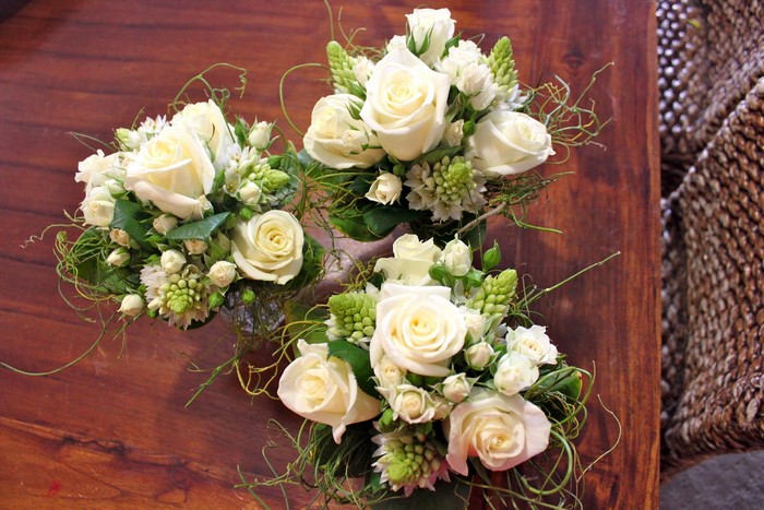 Three white rose bouquets on a wooden table