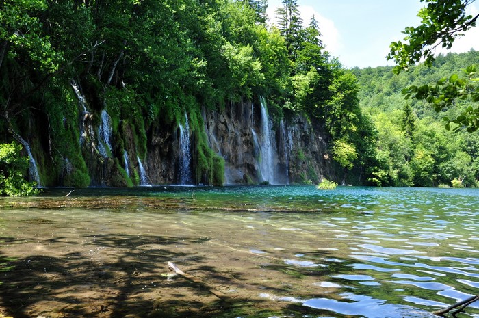 Waterfalls cascading down a rocky cliff into a clear lake