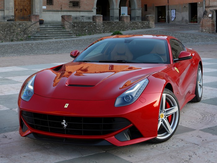 Red Ferrari F12berlinetta parked on cobblestone street