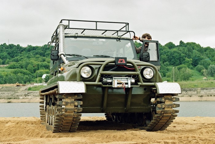 Green tracked UAZ vehicle with a man entering