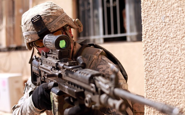 Soldier aiming a machine gun with a scope