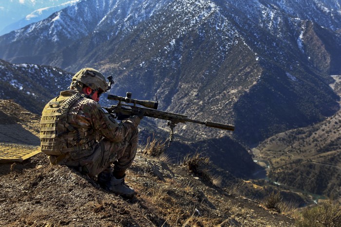 Soldier with sniper rifle in mountains