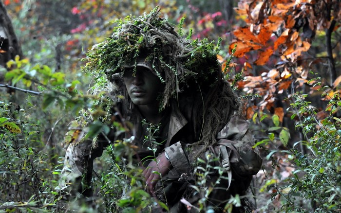 Soldier in camouflage ghillie suit in forest