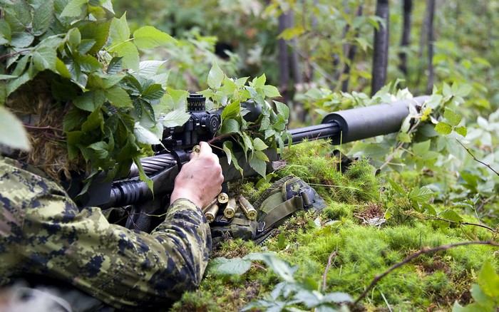 Soldier loading sniper rifle in forest