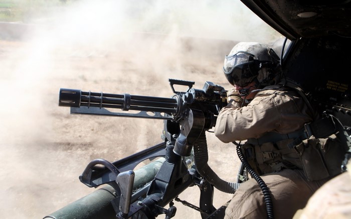Soldier firing a minigun from a helicopter