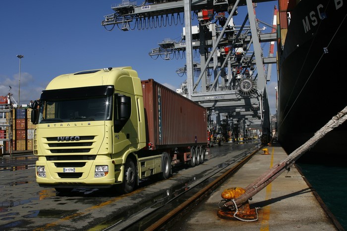Yellow Iveco Stralis Truck at Port with Ship and Cranes