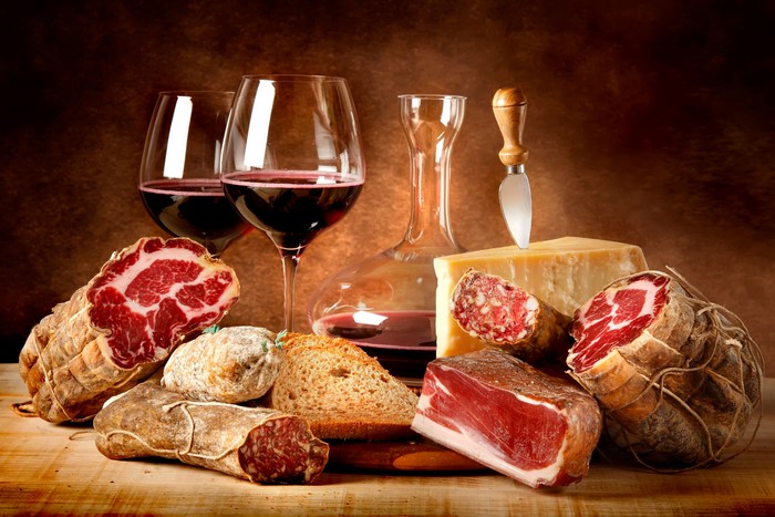 Still life with cured meats, cheese, bread, and red wine