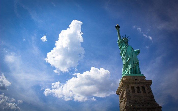 Statue of Liberty against a blue sky with clouds