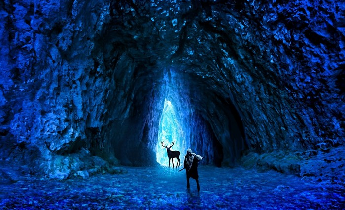 Man and deer in a glowing blue cave