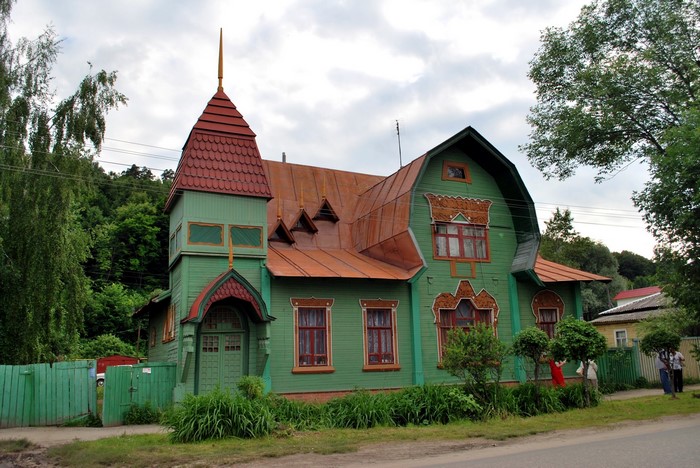 Green wooden house with red roof in Russia