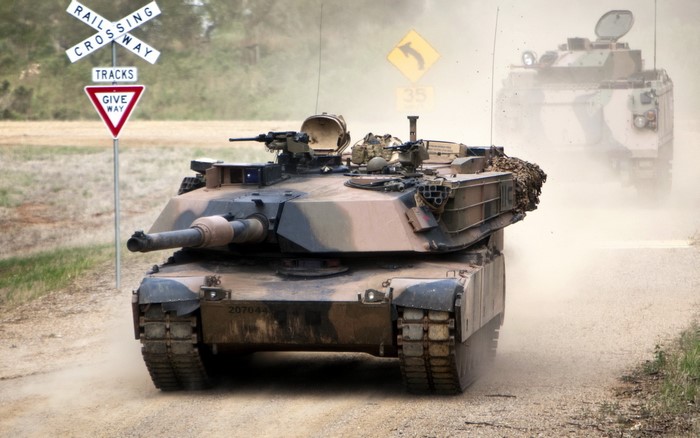 Tanks on a dusty road near a railway crossing