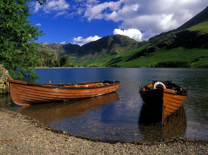 Two wooden boats on a lake with mountains in the background