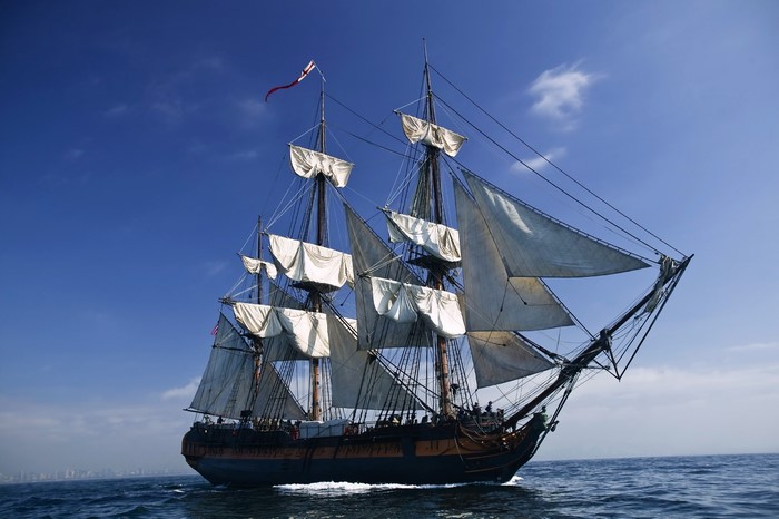 A tall sailing ship with white sails on the ocean