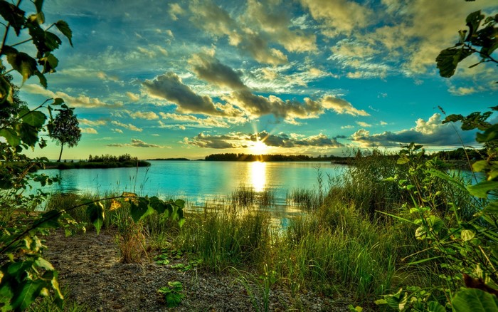 Sunset over a calm lake with trees and clouds
