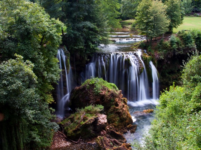 Waterfalls cascading over rocks surrounded by trees