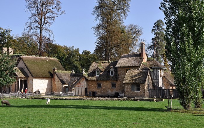 Thatched-roof houses in a rural setting with animals