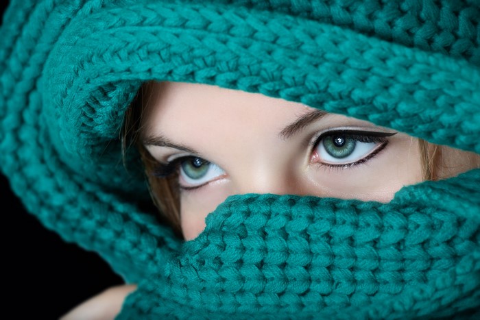 Close-up of a woman's eyes covered by a teal scarf