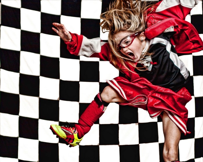 Girl in soccer uniform jumping in front of checkered background