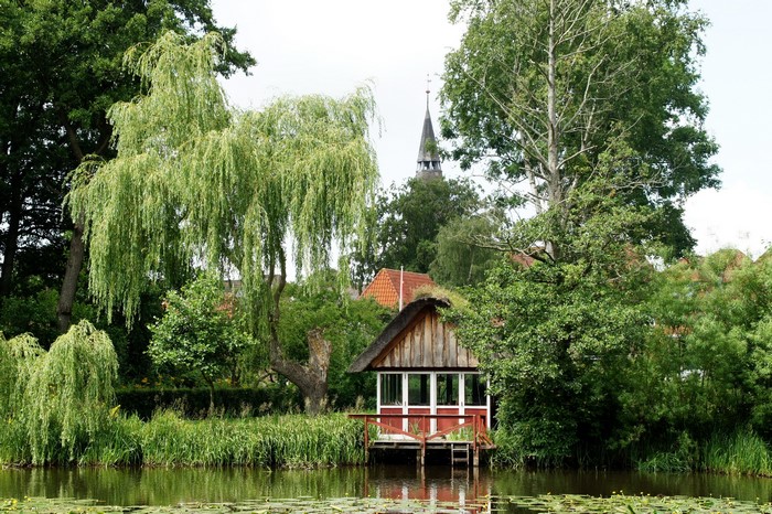 Boathouse by a river with a church spire