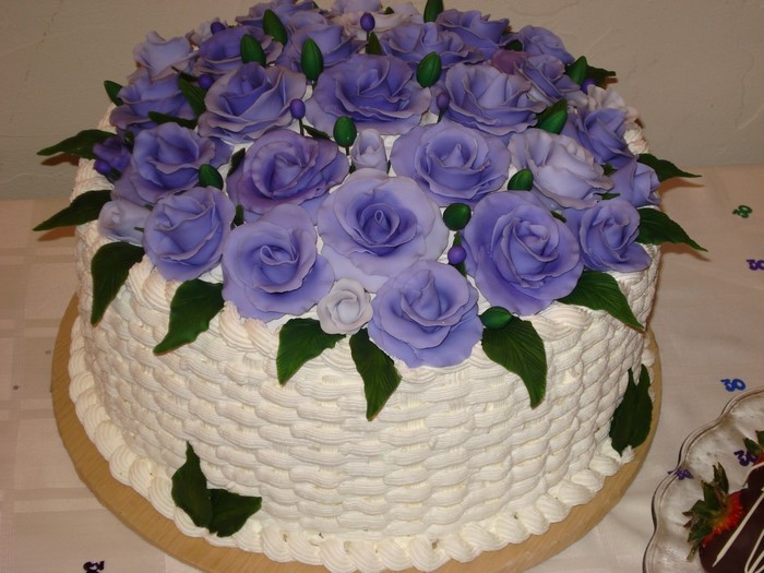 White cake with purple roses and green leaves