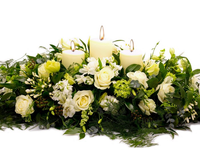 Floral arrangement with three lit candles