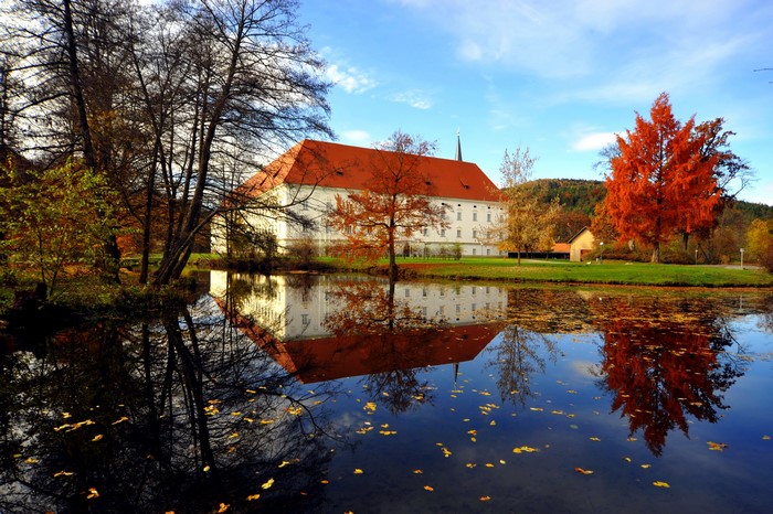 Monastery Viktring Klagenfurt reflected in a pond during autumn
