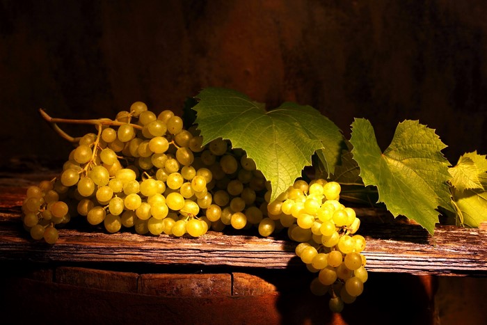 Grapes with leaves on a wooden surface