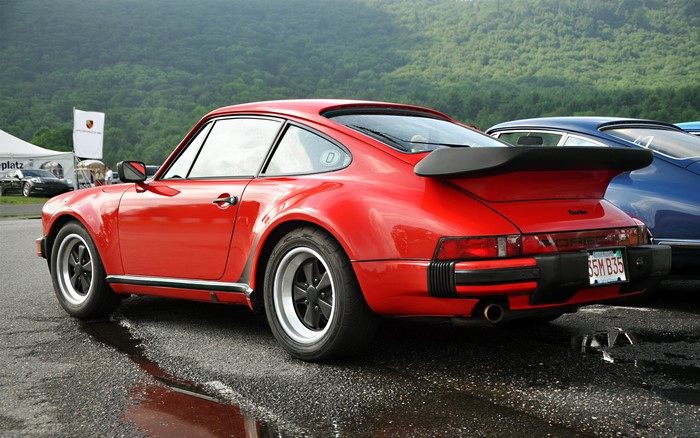 Red Porsche 911 Turbo parked on wet asphalt