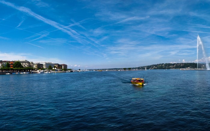 Yellow boat on a lake with a city and fountain