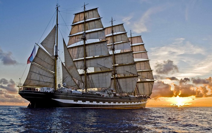 Tall ship sailing at sunset