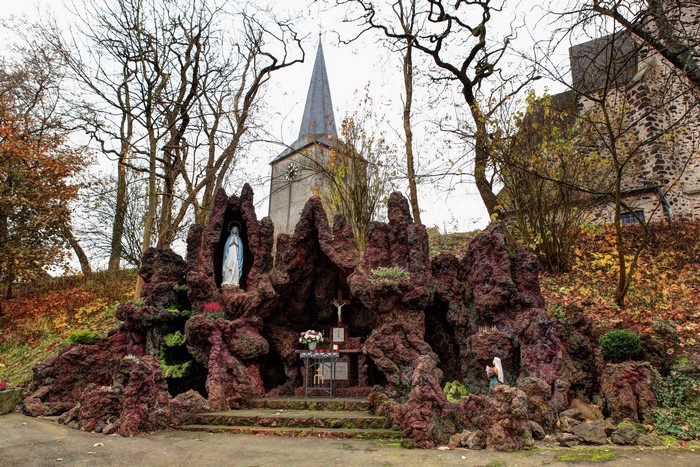 Grotto with Virgin Mary statue and church in Germany