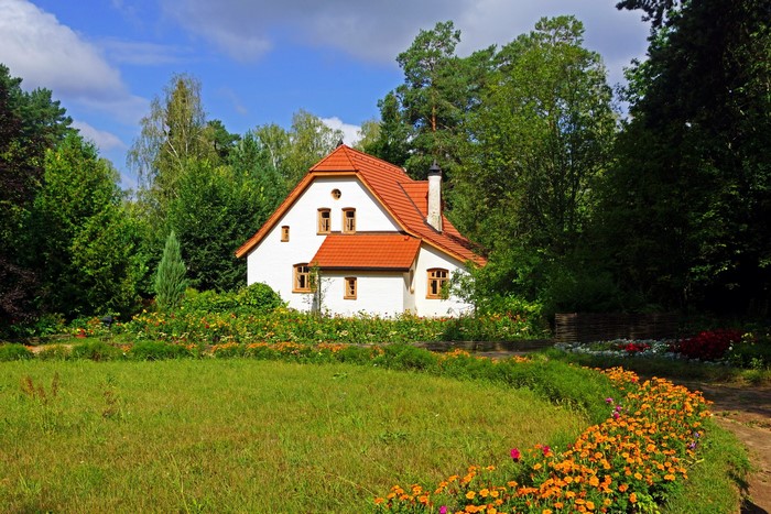 White house with orange roof surrounded by gardens and trees