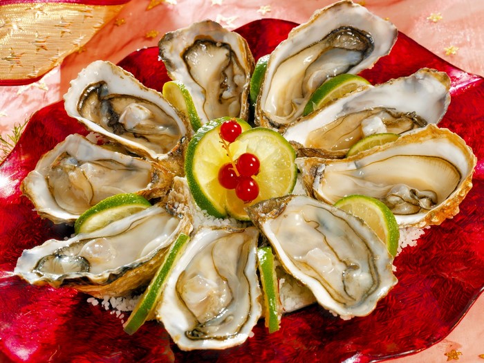 Oysters with lime and red currants on a red plate
