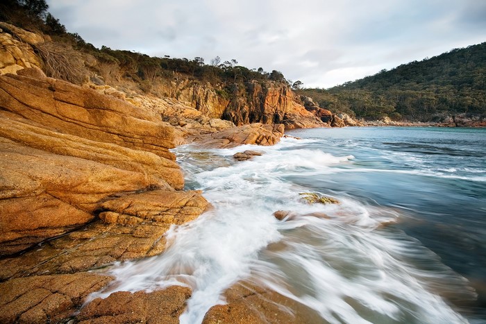 Waves crashing on rocky shore at Freycinet National Park, Tasmania, Australia