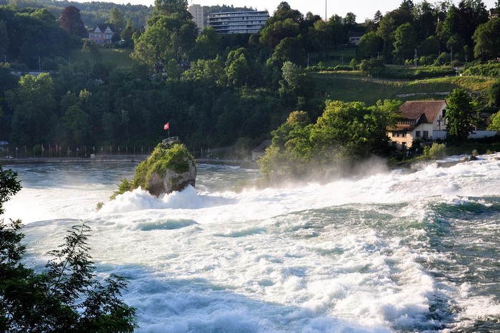 Rhine Falls in Switzerland with a rock and flag