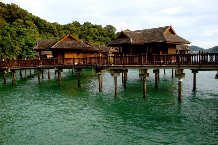 Tropical overwater bungalows on stilts in turquoise water