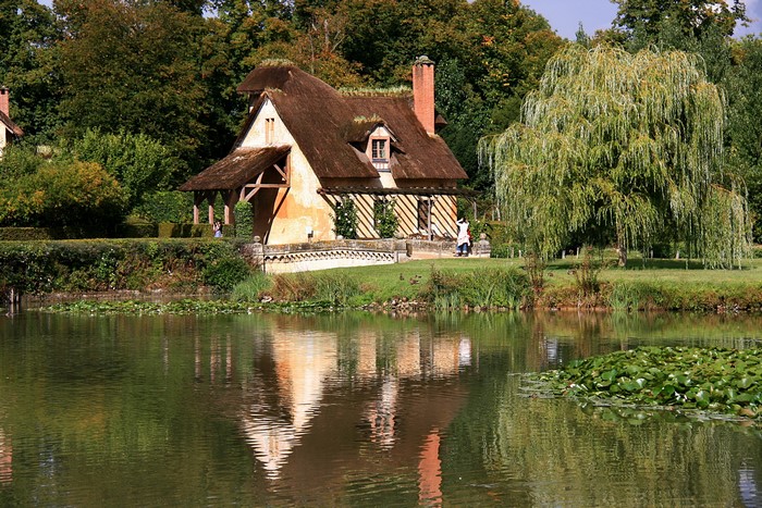 Thatched cottage by a pond in a park in France