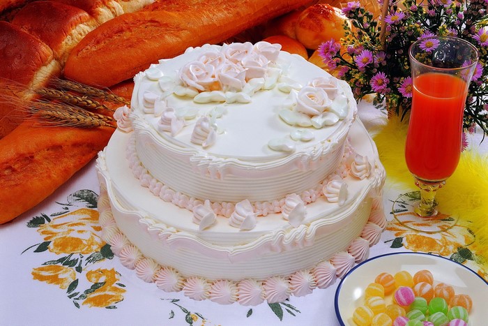 Two-tiered white cake with pink frosting and roses