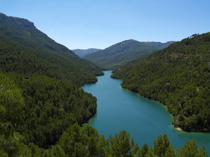 Turquoise lake surrounded by pine-covered mountains in Spain
