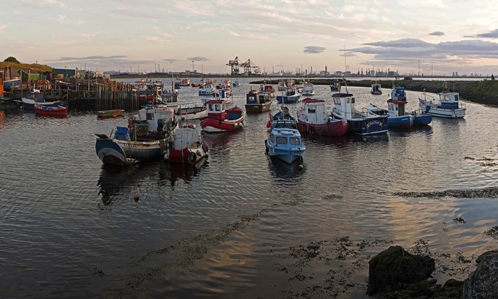 Boats docked in a harbor with industrial background