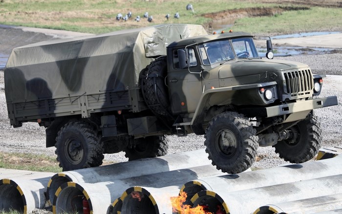 Military truck driving over concrete pipes with fire