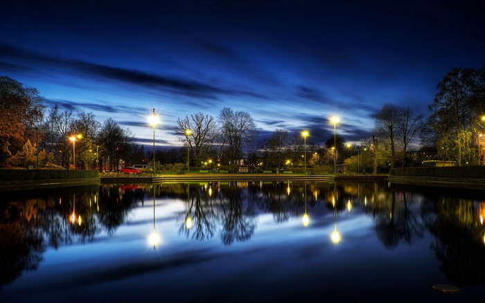 Park with pond and streetlights at dusk