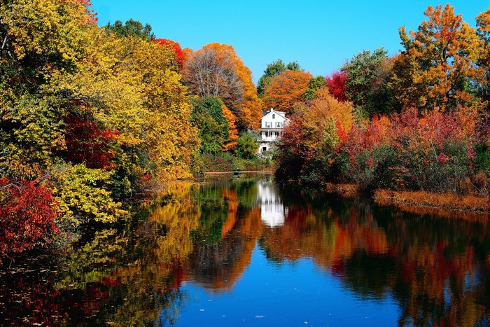 Autumn foliage reflected in a lake with a house