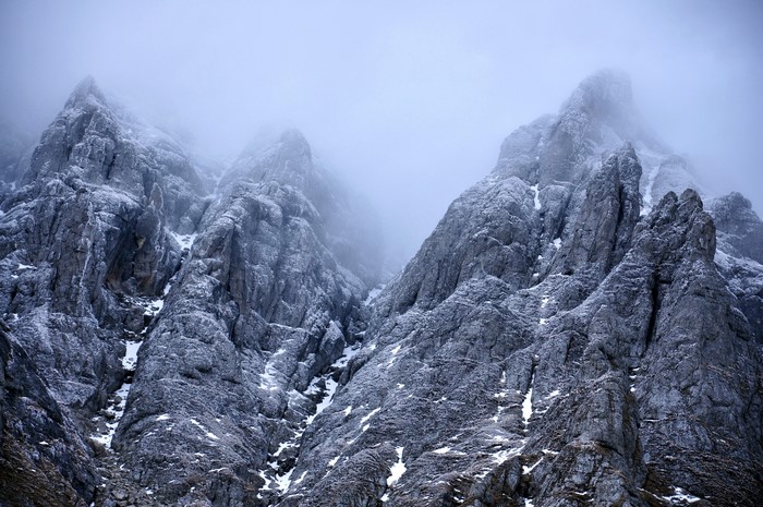 Snow-covered rocky mountains shrouded in mist