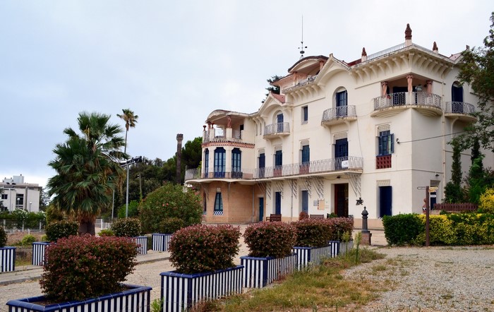 White building with balconies and palm trees in Spain