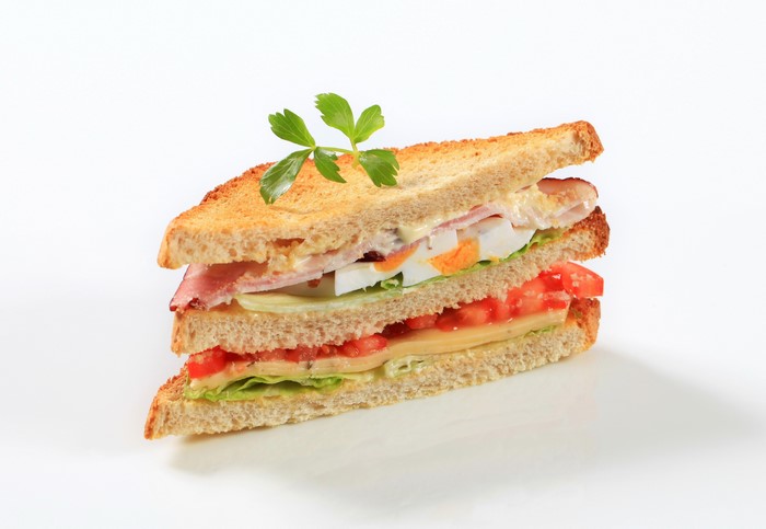 Triple-decker sandwich with ham, egg, tomato, and cheese