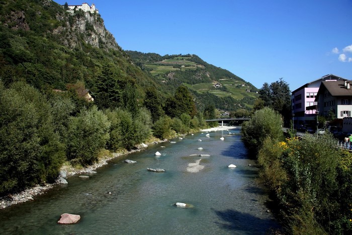 River flowing through a town with a castle on a hill