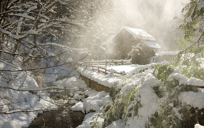Snowy winter scene with a rustic building and fence