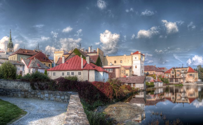 Town buildings reflected in water under cloudy sky